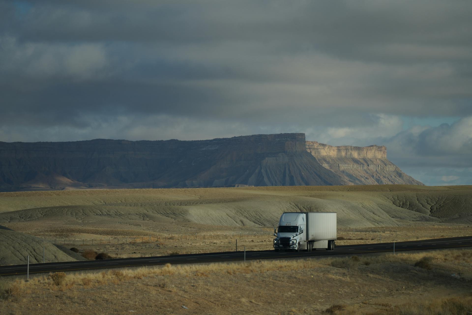 Semi truck silhouetted against a dramatic desert sky at sunset
