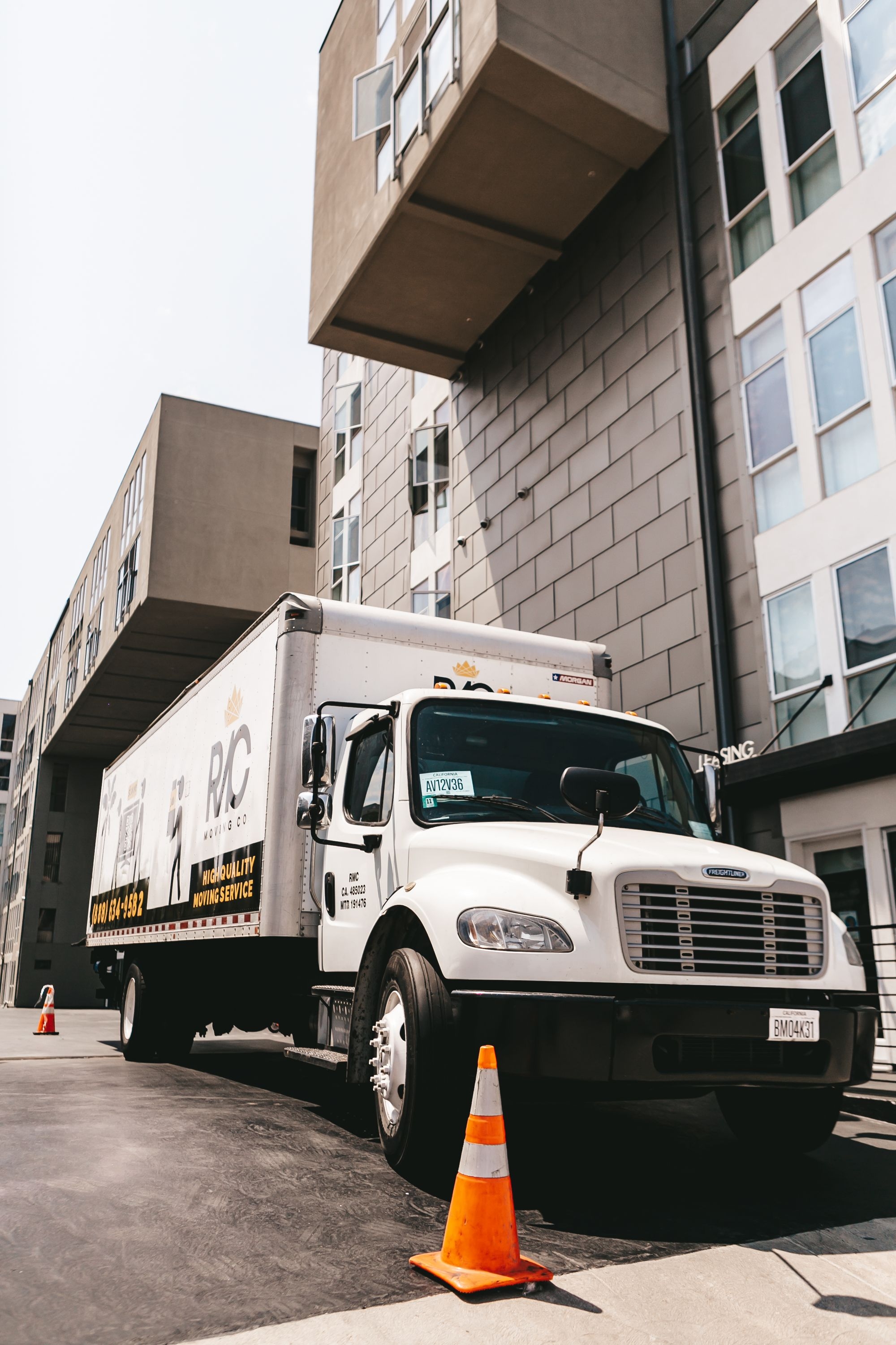 Freightliner M2 box truck (RJC Moving) parked outside a modern apartment building in California