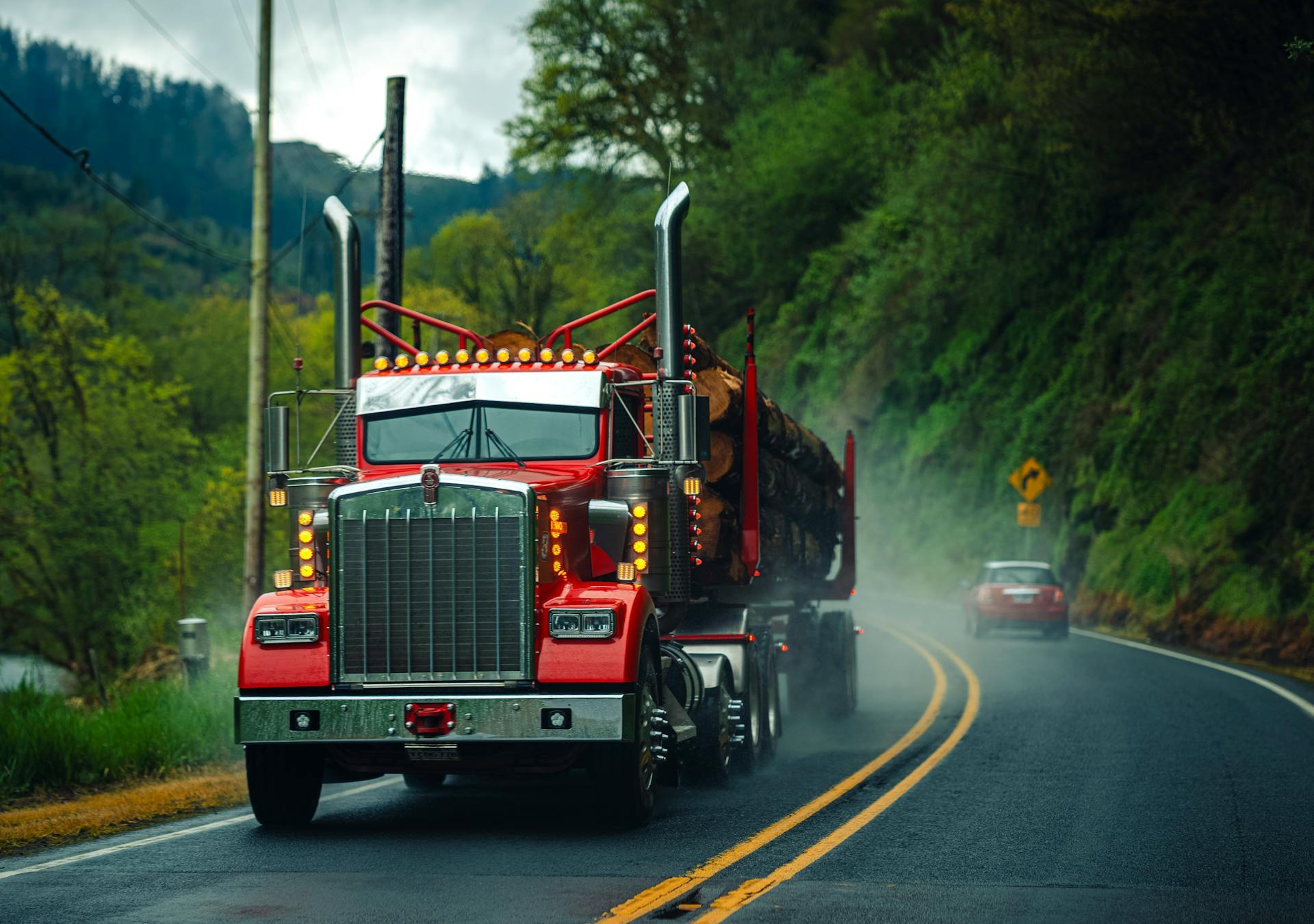 Red Kenworth semi truck on a Pacific Northwest highway at amber dusk